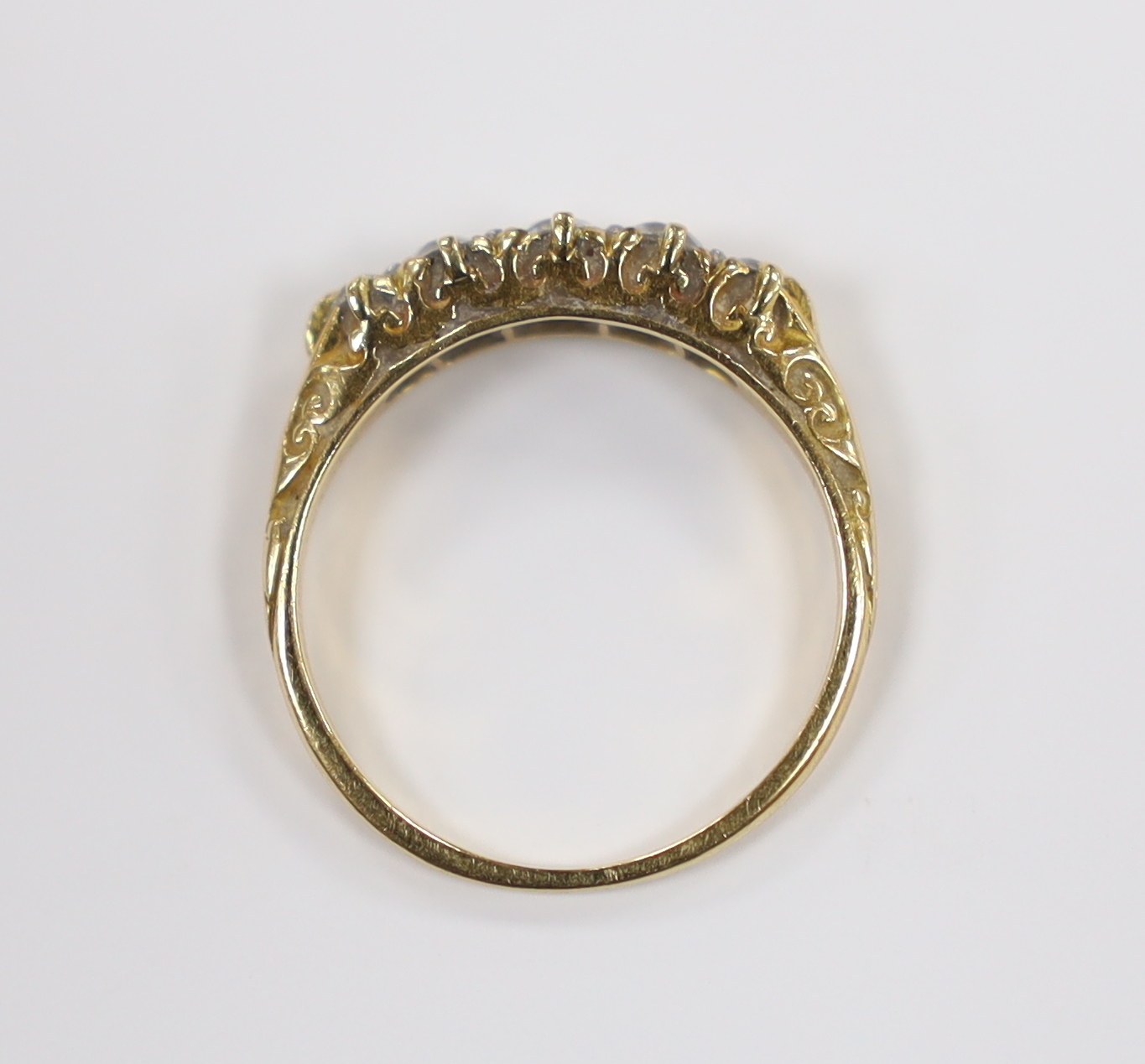 An early 20th century yellow metal and graduated five stone diamond set half hoop ring, size I, gross weight 2.1 grams.